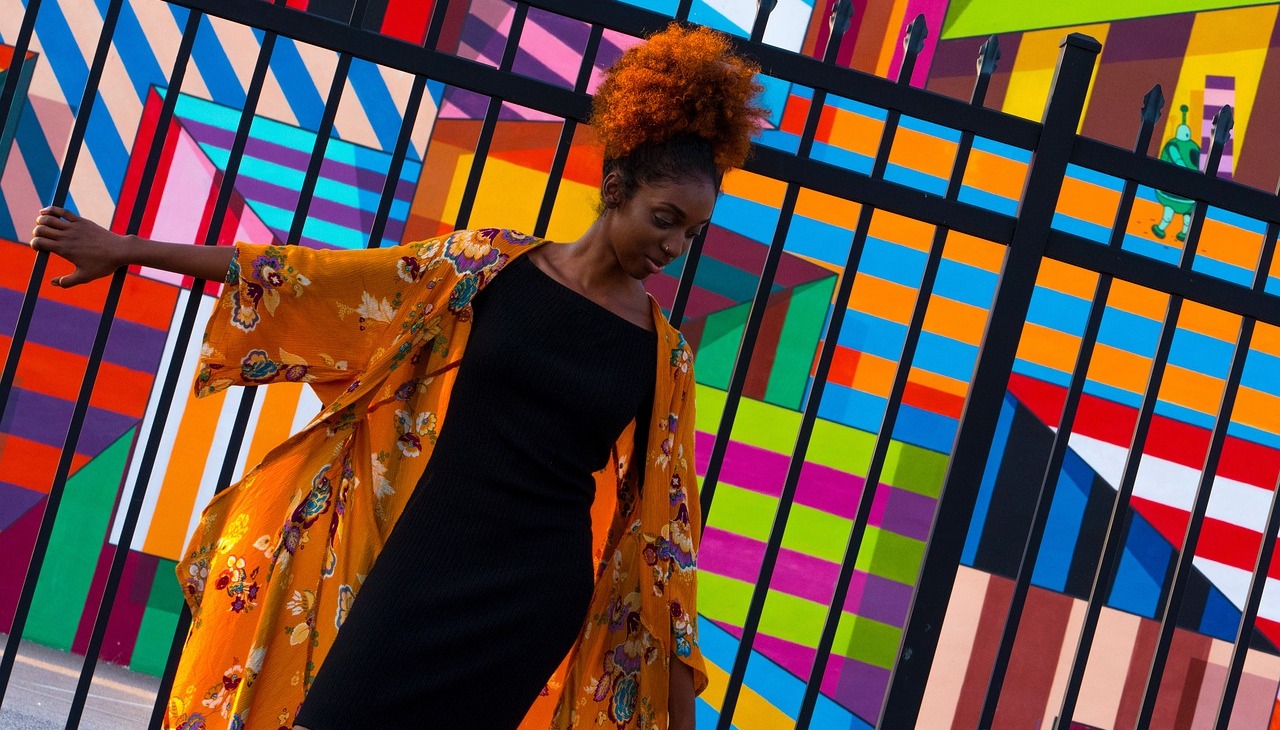 Black woman dancing with a colorful background.