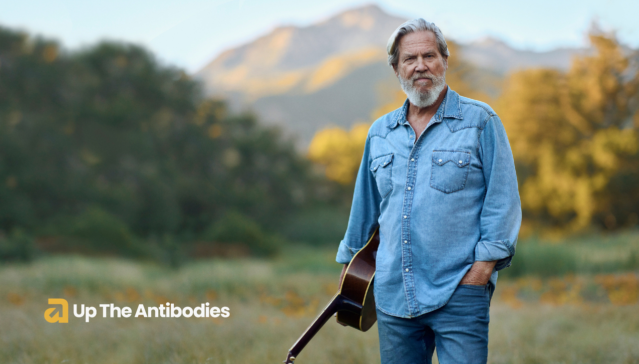 Jeff Bridges holding a guitar. Promo image of Up The Antibodies.