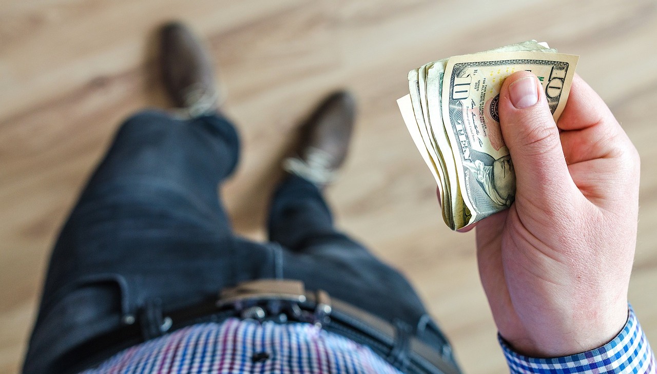 A person holds cash on his hand.