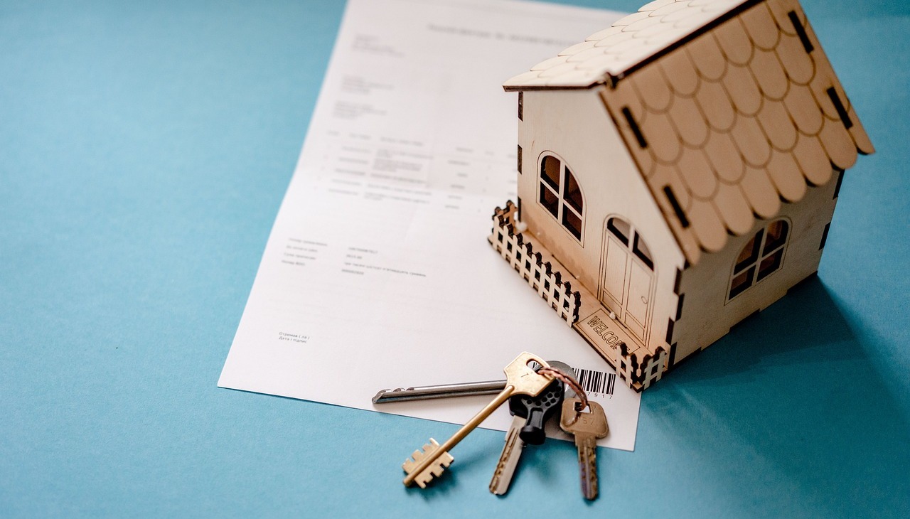 Toy house on top of a contract and next to a set of keys. Image to illustrate mortgage transactions. 