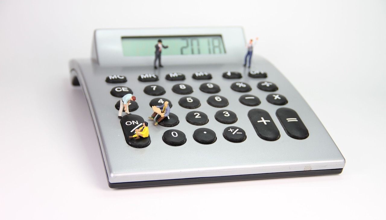 A calculator with small toys placed on the keyboard. Image to illustrate financial study. 