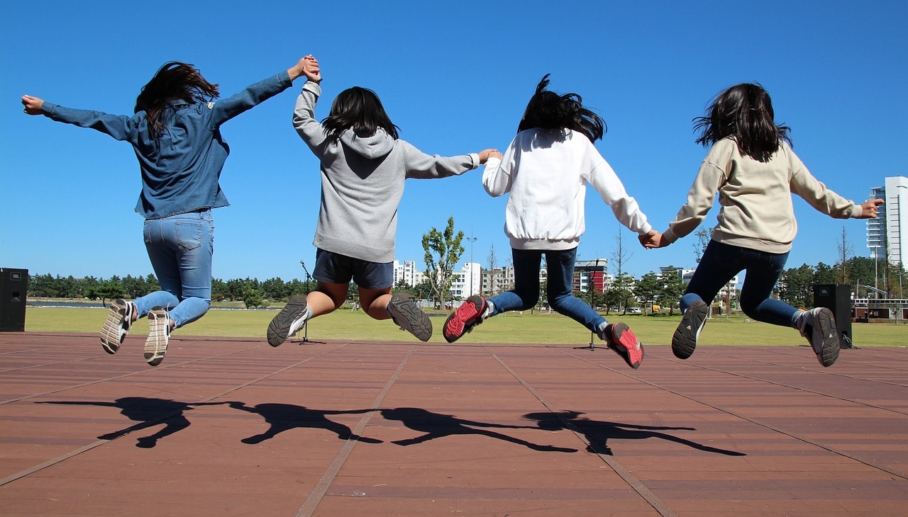 Children holding hands jumping on a track field. 