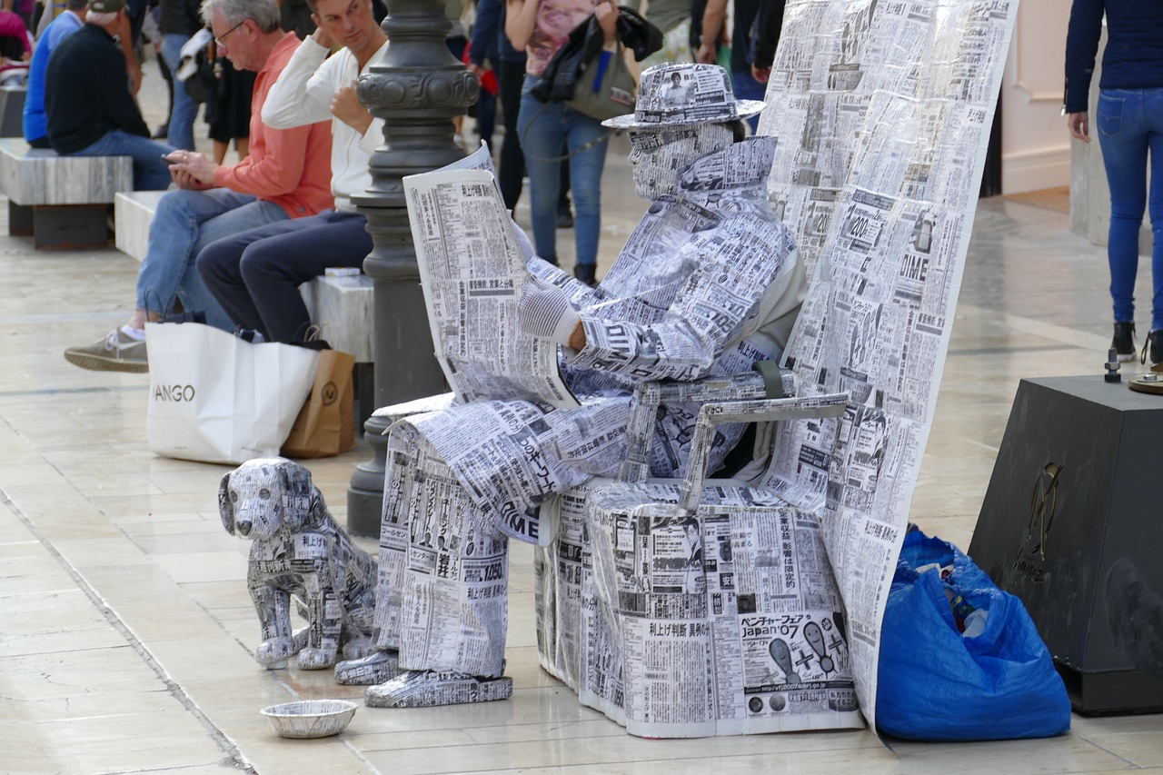 A street artist covered with newspapers. 