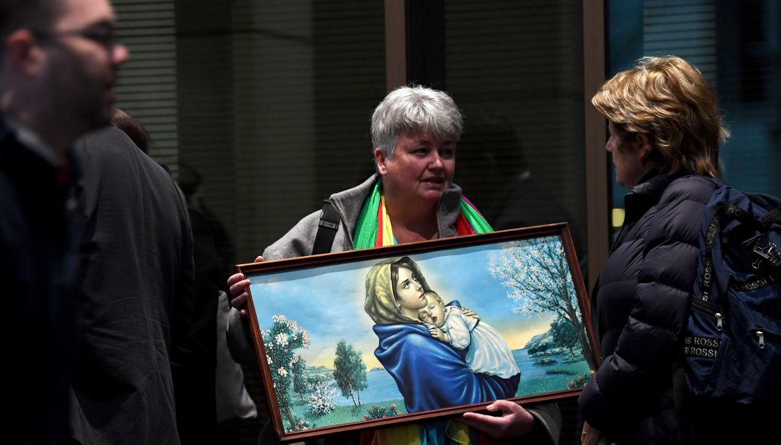 A victim advocate holds a painting of Mary and Jesus outside the Melbourne Magistrates Court in Melbourne, 26 July 2017. Cardinal Pell, 76, Australia's most senior Catholic, was charged on 29 June 2017, with multiple counts of historical sexual assault offences. EPA/JOE CASTRO 
