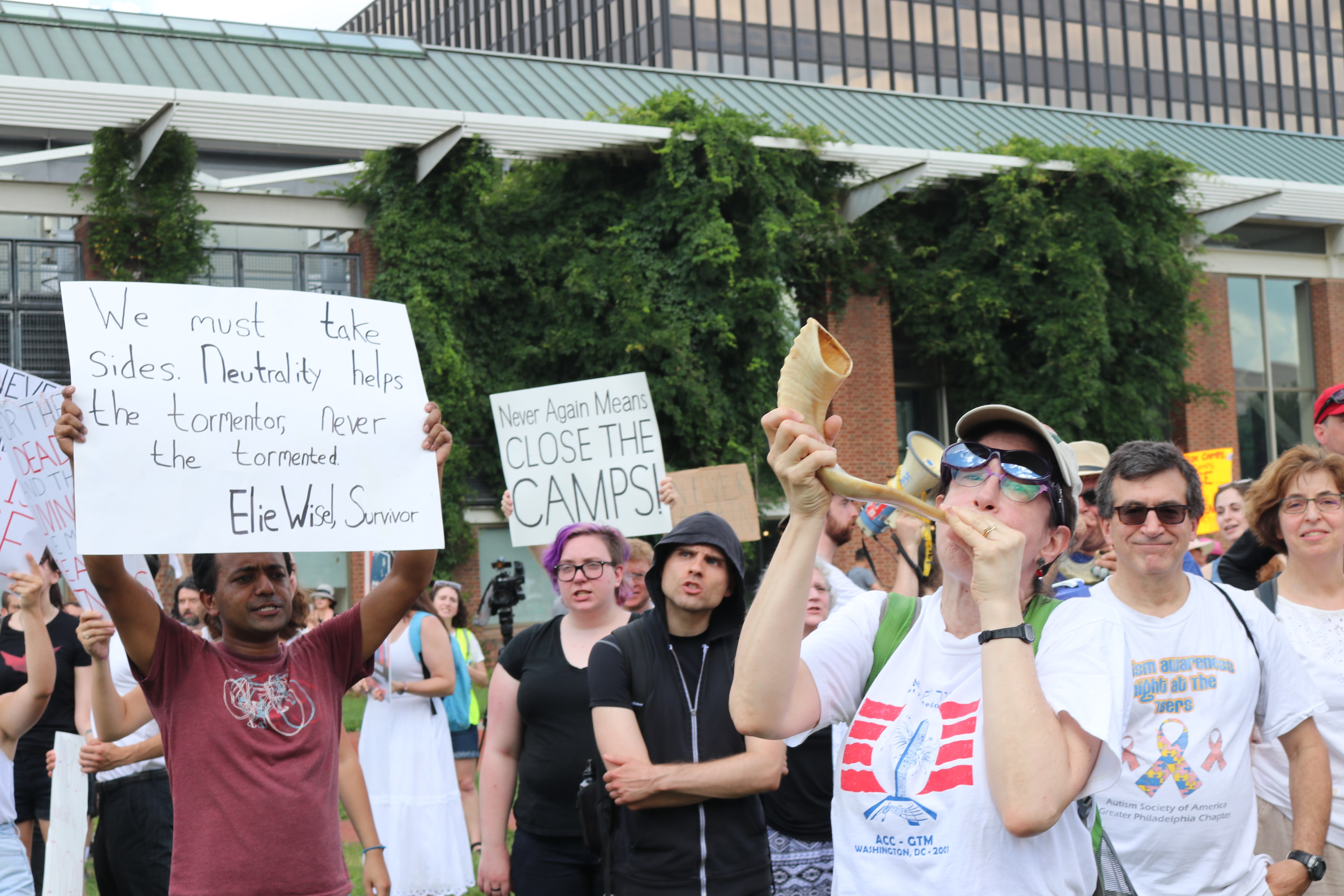 Cantor Naomi Hirsch blows the shofar, a Jewish instrument, as a call to action at the Philadelphia protest on Independence Day. 