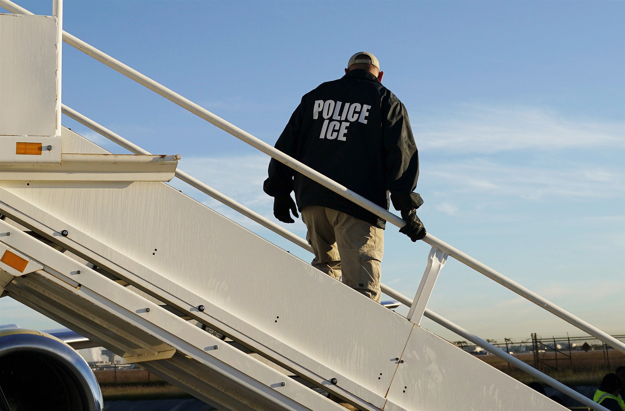 An officer watches as immigrants are deported on a flight to El Salvador by U.S. Immigration and Customs Enforcement out of Houston in 2018. David J. Phillip / AP file
