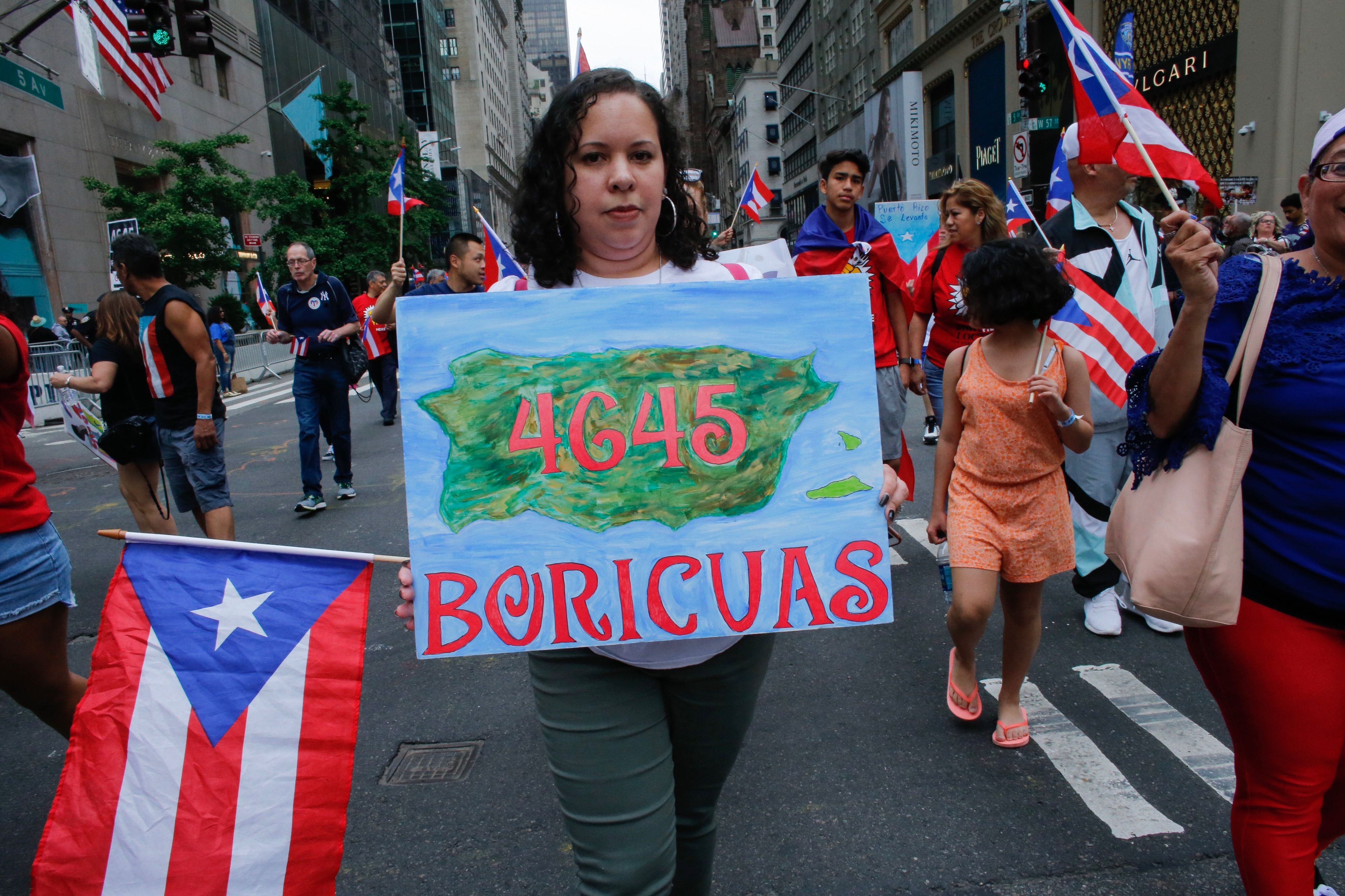 A woman displays a sign with the death toll for Hurricane Maria estimated by the recent Harvard study on June 10, 2018 at the annual Puerto Rican Day parade on Fifth Avenue in New York City. EFE