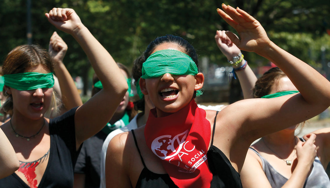 SANTIAGO, CHILE - DECEMBER 06: Demonstrators wearing green scarves covering their eyes sing and dance in a feminist flash mob that plays "A Rapist in Your Way" in protest of violence against women on December 6, 2019 in Santiago, Chile. The song, written by local feminist group Lastesis, is becoming an international feminist phenomenon. (Photo by Marcelo Hernandez/Getty Images)