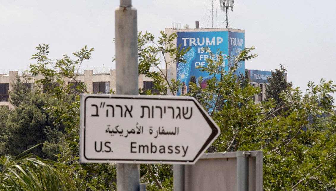 Un cartel en el que se lee "Trump es amigo de Sion", colocado detrás de una señal indica la dirección hacia la Embajada de Estados Unidos, con motivo de su inauguración en Jerusalén, Israel, el lunes 14 de mayo de 2018. EFE/ Atef Safadi