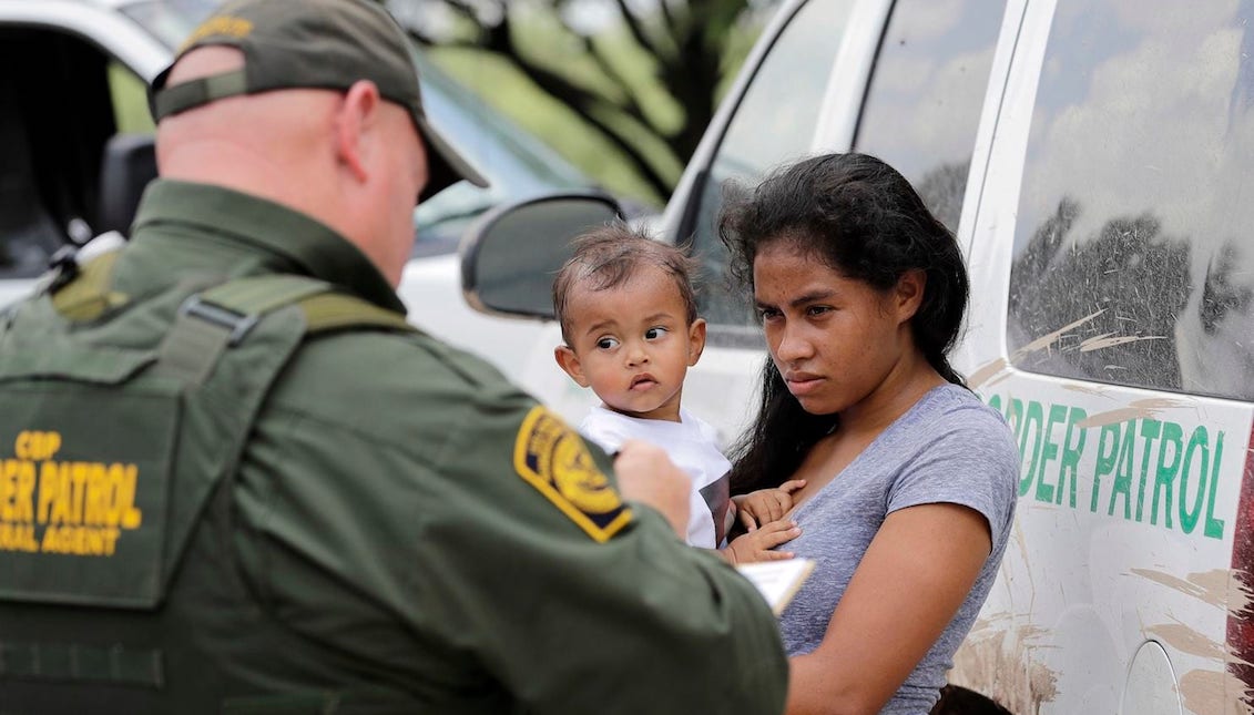 Una mujer hondureña, sosteniendo a su hijo de 1 año, se rinde ante agentes de la Patrulla Fronteriza de los EE.UU. cerca de McAllen, Texas (David J. Phillip/AP)