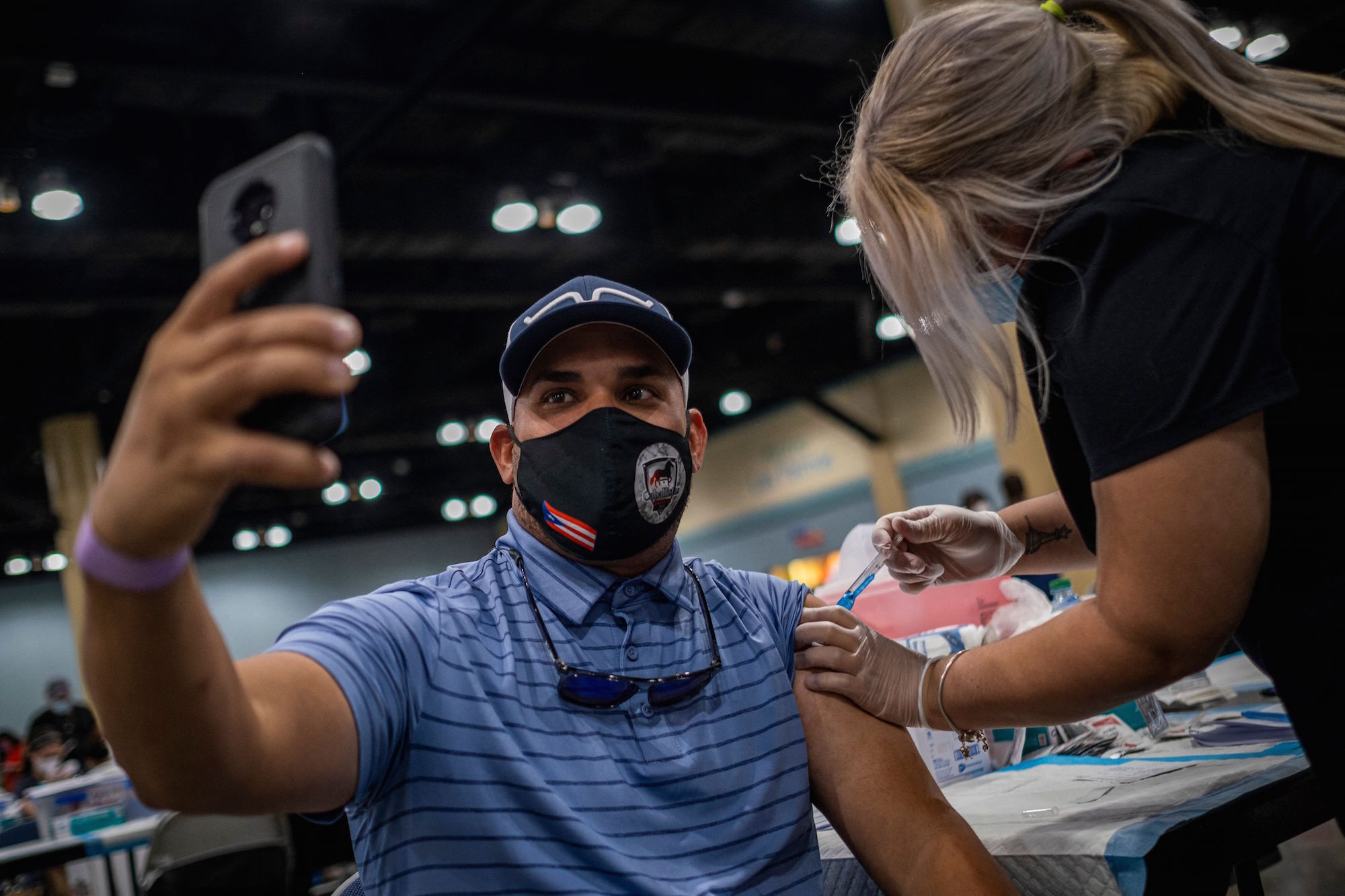 A man takes a selfie as he receives the Johnson and Johnson Covid-19 vaccine at a mass vaccination event at the Puerto Rico Convention Center in San Juan, Puerto Rico on March 31, 2021. (Photo by Ricardo ARDUENGO / AFP) (Photo by RICARDO ARDUENGO/AFP via Getty Images)