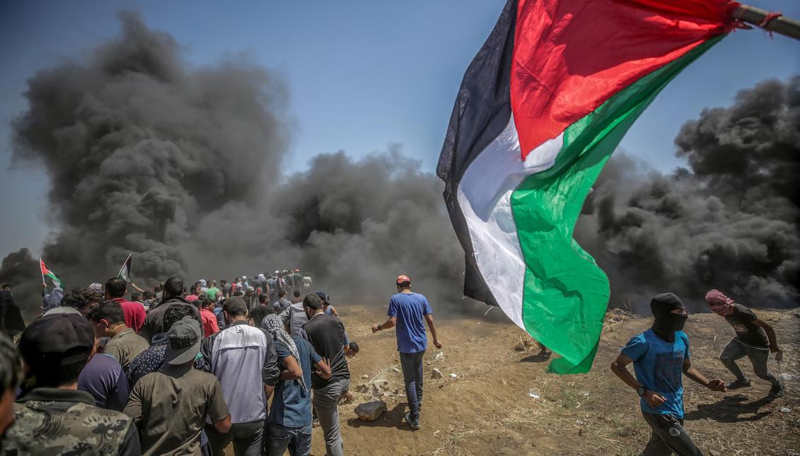 Manifestantes corren para protegerse del gas lacrimógeno lanzado por soldados israelíes durante unas protestas en la frontera de Gaza e Israel el lunes 14 de mayo de 2018. EFE/ Mohammed Saber